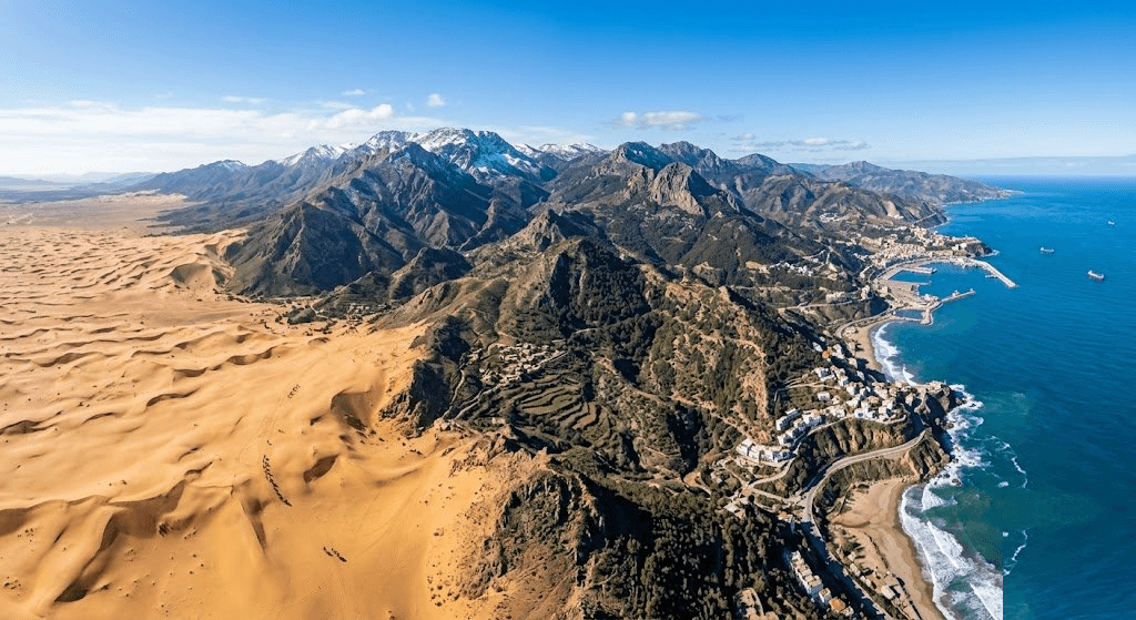 Paysage algérien combinant dunes du Sahara, montagnes rocheuses et littoral méditerranéen sous un ciel clair.